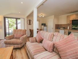 A living room with a sofa and dining area at Chestnut Timber Lodge in Keswick