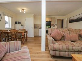 A living room with a dining area and kitchen appliances at Chestnut Timber Lodge in Keswick