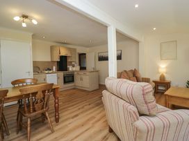 A kitchen and living area with a dining table and chairs at Chestnut Timber Lodge in Keswick
