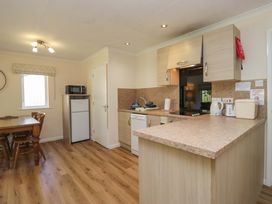 A kitchen with wooden dining table and appliances at Chestnut Timber Lodge in Keswick