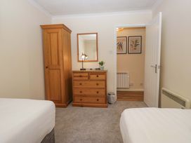 A bedroom with a bed, wardrobe, and chest of drawers at Chestnut Timber Lodge, Keswick