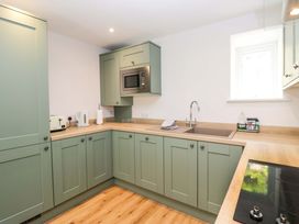 A kitchen with cabinets, sink, microwave, and kettle at Riverside Cottage No 4 in Keswick