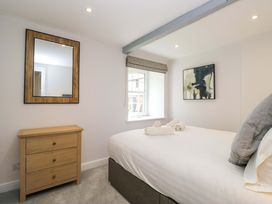 A bedroom with a bed, drawer, and a window at Riverside Cottage No 4, Keswick