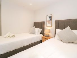 A bedroom with two beds and a lamp on a nightstand at Riverside Cottage No 4 Keswick