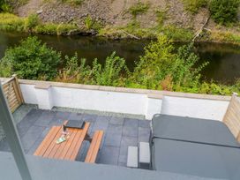 An outdoor area with a patio table and hot tub at Riverside Cottage No 4 in Keswick