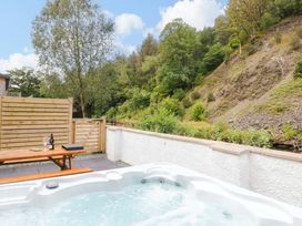 A hot tub and table with drinks in an outdoor area at Riverside Cottage No 4 Keswick