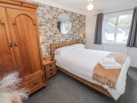 A bedroom with a bed and wooden furniture at Chellowdene Cottage in Falmouth