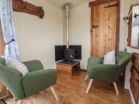 A small sitting area with two green armchairs a wood burning stove and a wooden door at The Coop Aston near Woore