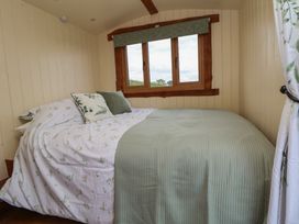 A bedroom with a bed covered in floral and green bedding next to a window at The Coop in Aston near Woore