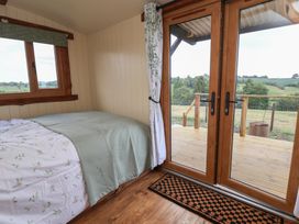 A bedroom with a bed near wooden framed glass doors leading to a deck at The Coop in Aston near Woore