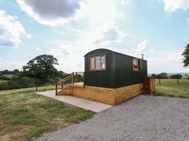 A small cabin on a wooden platform with gravel driveway and grassy field at The Coop in Aston near Woore