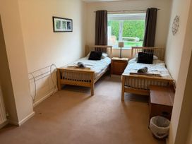 A bedroom with two beds and a nightstand at Jacuma in Rhosneigr