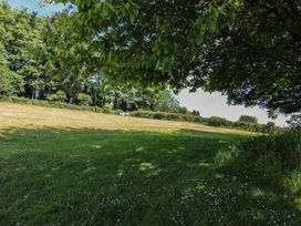 A garden with a grass area and trees at November Cottage in Dittisham