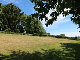 An outdoor area with grass, trees, and a bench at November Cottage in Dittisham