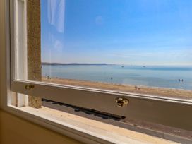 A view from a window overlooking the beach and sea at 123 On The Sea – Victoria’s Place in Weymouth