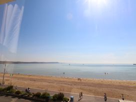 A beach view with people walking along the shore at 123 On The Sea – Victoria’s Place in Weymouth