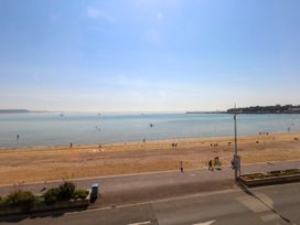 A beach with people walking and a pier at 123 On The Sea – Victoria’s Place in Weymouth