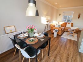A dining room with a table set for two and a sofa at Nene's Nest in Alnwick
