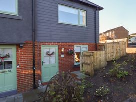 An exterior view of a house with green doors and a wooden fence at Nene's Nest Alnwick