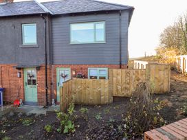 A house with green doors and windows next to a garden at Nene's Nest in Alnwick