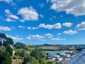 A coastal town with houses boats and a marina surrounded by hills and trees under a blue sky with clouds at Cranford in Salcombe
