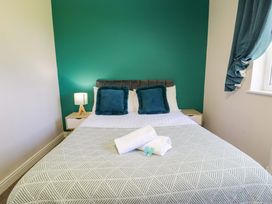 A bedroom with a bed, bedside table and towels at Woodlands Retreat in Llanfwrog near Ruthin