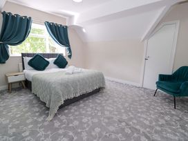 A bedroom with a bed and chair at Woodlands Retreat Llanfwrog near Ruthin