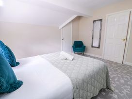 A bedroom with a bed and chair at Woodlands Retreat in Llanfwrog near Ruthin