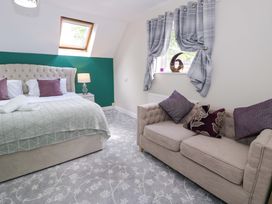 A bedroom with a bed and a sofa at Woodlands Retreat Llanfwrog near Ruthin