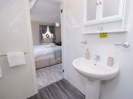 A bathroom with a wash basin and a bedroom door at Woodlands Retreat Llanfwrog near Ruthin
