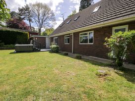 A garden with a house and a spa at Woodlands Retreat in Llanfwrog near Ruthin