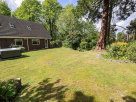A garden with a house and hot tub at Woodlands Retreat Llanfwrog near Ruthin