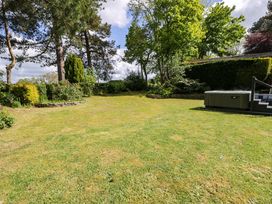 A garden with a hot tub and trees at Woodlands Retreat Llanfwrog near Ruthin