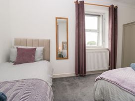 A bedroom with two beds and a mirror at 3 Nixon Terrace near Broughton Moor
