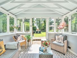 A conservatory with seating and a garden view at 2 Pigsfoot Cottages Ash Thomas near Halberton, Devon