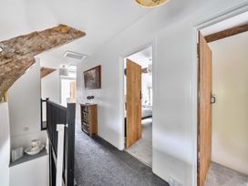 A hallway with wooden doors and a bookshelf at 2 Pigsfoot Cottages, Ash Thomas near Halberton, Devon