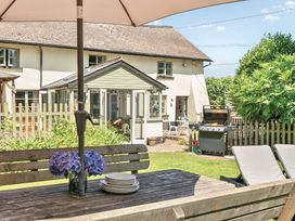 An outdoor dining area with a table and grill at 2 Pigsfoot Cottages Ash Thomas near Halberton, Devon