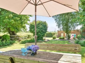 An outdoor dining area with flowers and glasses at 2 Pigsfoot Cottages Ash Thomas near Halberton, Devon