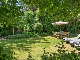 A garden with a table and chairs under a parasol at 2 Pigsfoot Cottages Ash Thomas near Halberton, Devon