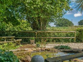 A garden with a table and benches near a pond at 2 Pigsfoot Cottages Ash Thomas near Halberton, Devon