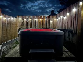A hot tub surrounded by wooden fencing and lights at Shepherds Retreat Maxworthy near Crackington Haven