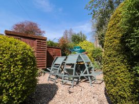 A garden area with two blue wooden chairs on gravel near wooden sheds and bushes at The Green in Lastingham