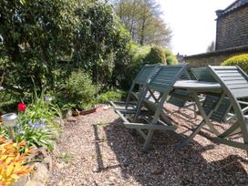 An outdoor patio area with a table and chairs on a gravel surface next to a garden with plants and flowers at The Green in Lastingham