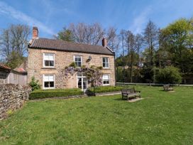 A stone house with a tiled roof and purple flowers on the front at The Green in Lastingham