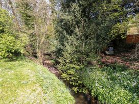 A small stream running through a garden area with grass trees and white flowers at The Green in Lastingham