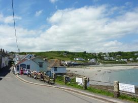 A beach with people and houses along the shore at The Mariners in Coverack