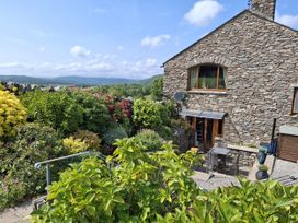 A garden with a stone house and seating area at Horse and Farrier Barn in Newton in Cartmel near Cartmel