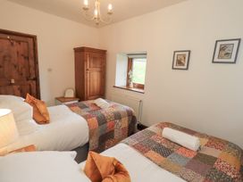 A bedroom with two beds and a wardrobe at Horse and Farrier Barn in Newton in Cartmel near Cartmel