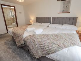A bedroom with two beds and an ensuite bathroom at Horse and Farrier Barn in Newton in Cartmel near Cartmel