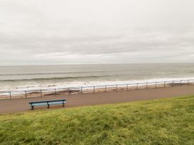 A coastal promenade with a blue bench and railing overlooking the sea and a grassy slope at Wonderland in Tweedmouth Berwick-Upon-Tweed